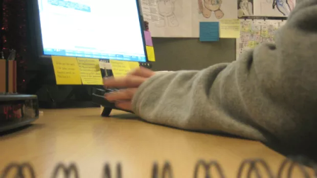 An image of a desk in an office with an anonymous workers hands in front of a computer.