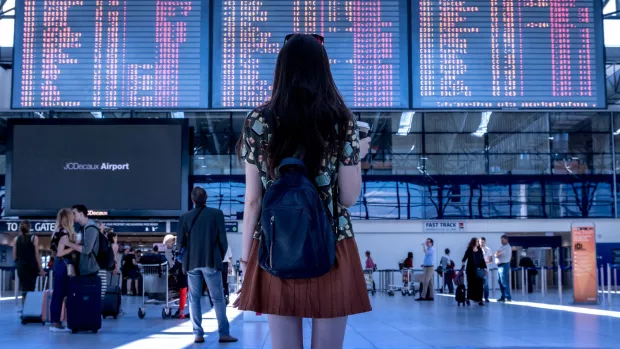A young woman looks at a giant airport departure board