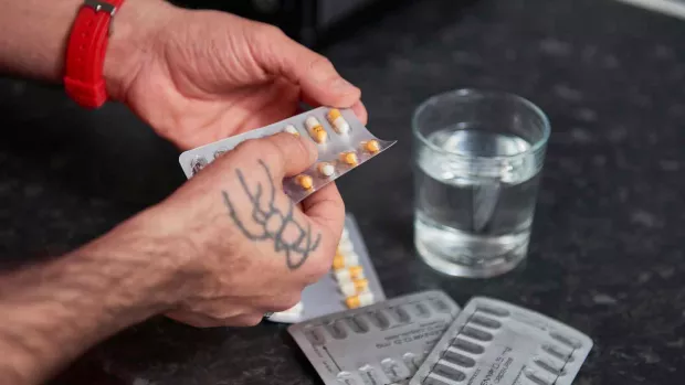 Photo: close up of man taking pills