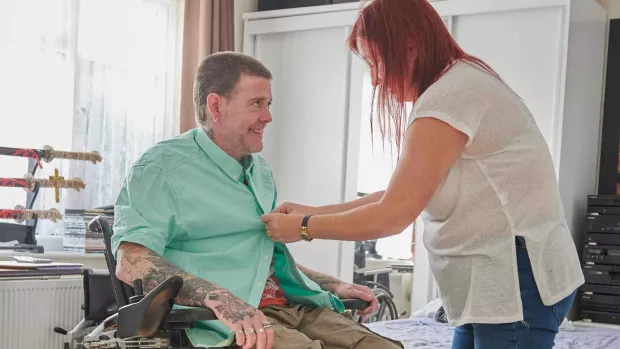 Photo: Woman helping dress her husband who has MS