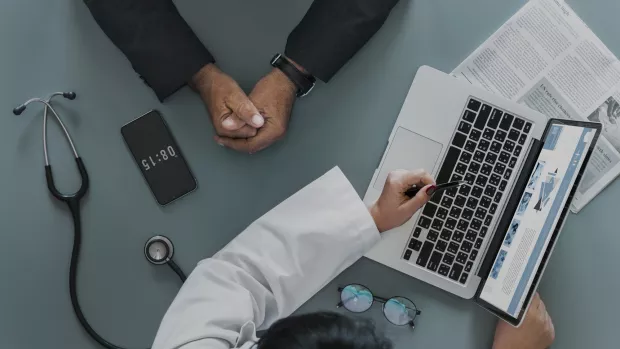 Doctor showing someone a web page on a laptop