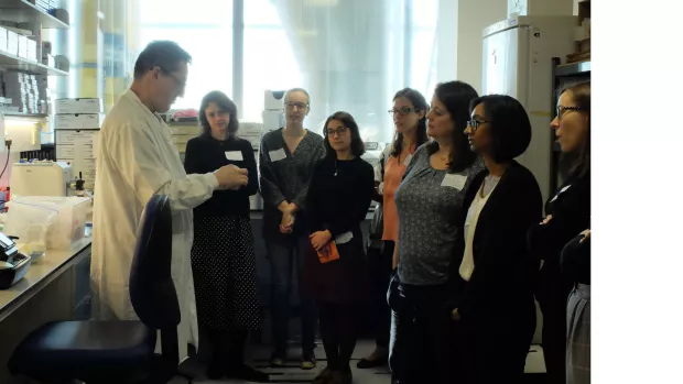 People in a lab listening to a researcher 