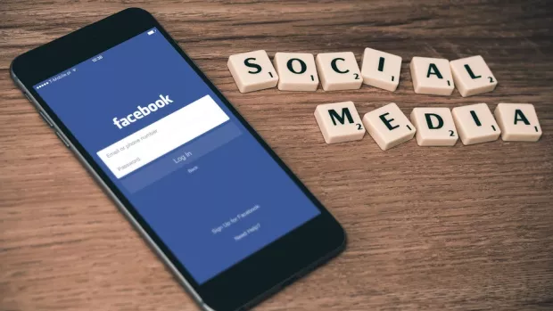 Photo: phone with Facebook logo next to scrabble tiles spelling out social media