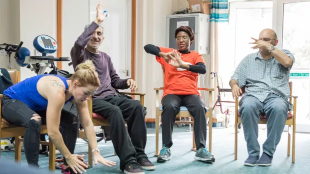 Four people exercising seated on chairs