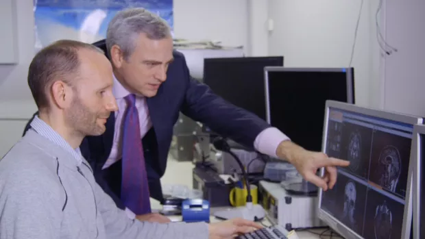 Jeremy Chataway looks at an MRI image on a screen with his colleague