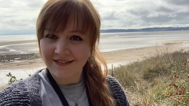 Kristen selfie smiling to camera with sea behind her.