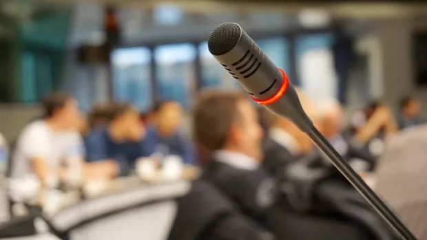 Podium microphone with blurred people sitting in the background