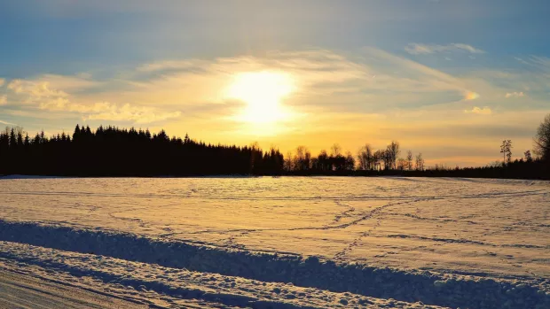 The sun sets over a field of snow