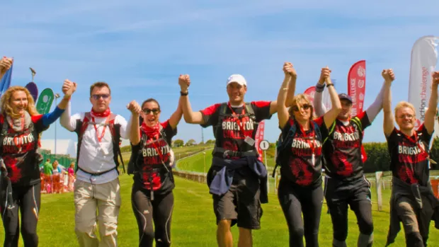 People at the finish line of a walking event with their hands in the air