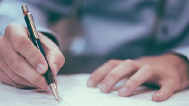 Man in shirt writing on a piece of paper