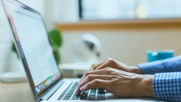 Hands typing on a laptop resting on a table