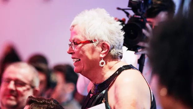 Judy stands at her table smiling at an event