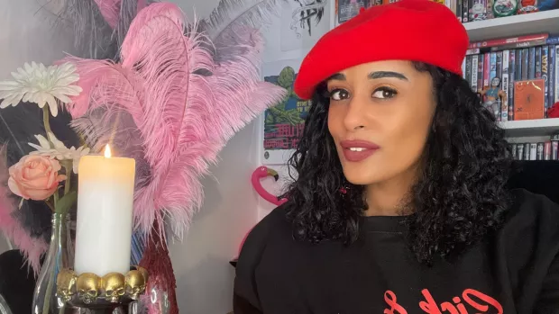 Roxanne pictured at home sitting by a candle and a vase full of pink feathers.