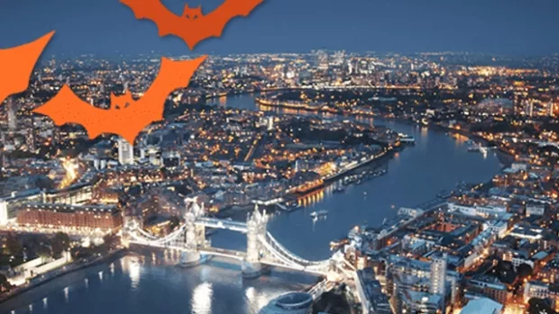 Aerial shot of London at night, with orange bats in the corner