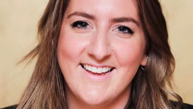 Emily has grey blue eyes, brown hair and is smiling to camera