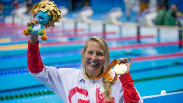 Stephanie picture by pool in Rio at Paralympics holding up gold medal and smiling