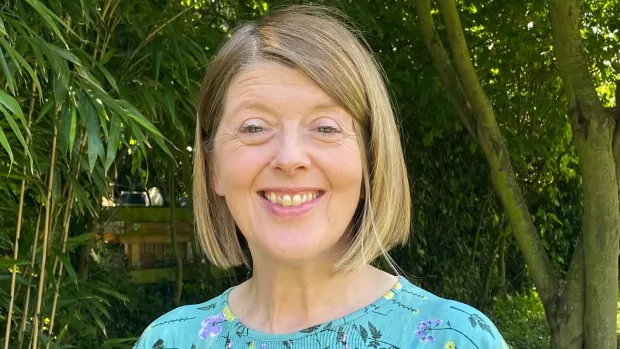 Headshot of Sue, outside and smiling. She has blonde hair in a bob.