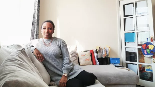 Rebbecca sits on her sofa looking at the camera