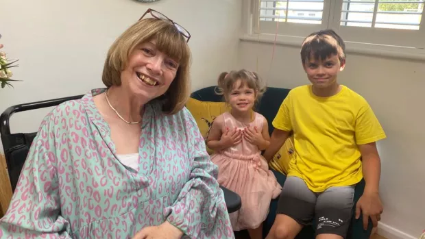 Carol sits with her two young grandchildren.