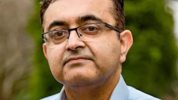 Dr Waqar Rashid, a head shot of a man in blue shirt and glasses with dark brown hair