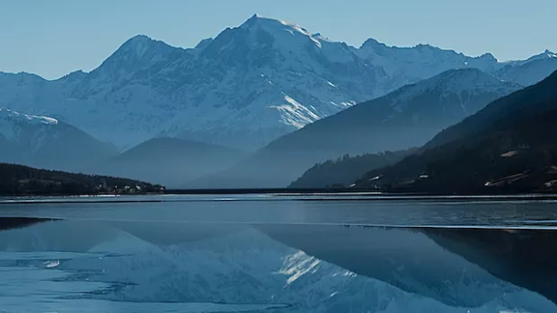 white mountains reflected in a blue lake