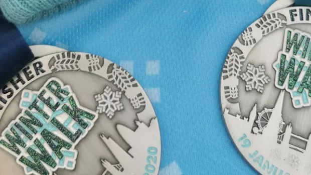 Two silver winter walk medals on a blue background