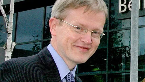 A man in a pin-stripe jacket smiling