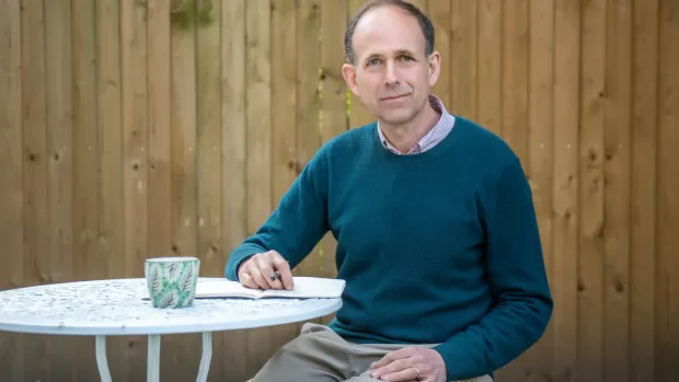 Photo of our current CEO, Nick Moberly, at home, working in his garden looking pensive with a slight smile.