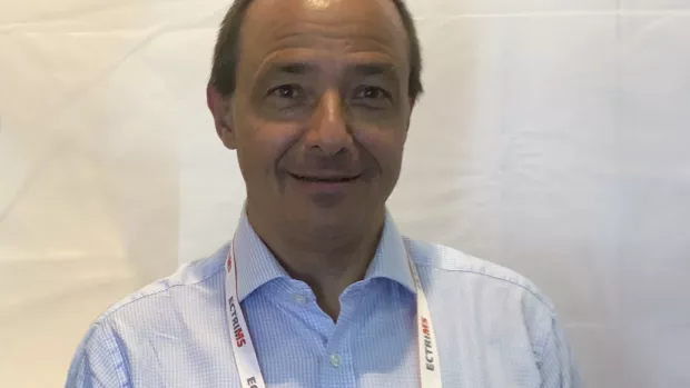 A man in a blue checked shirt smiling