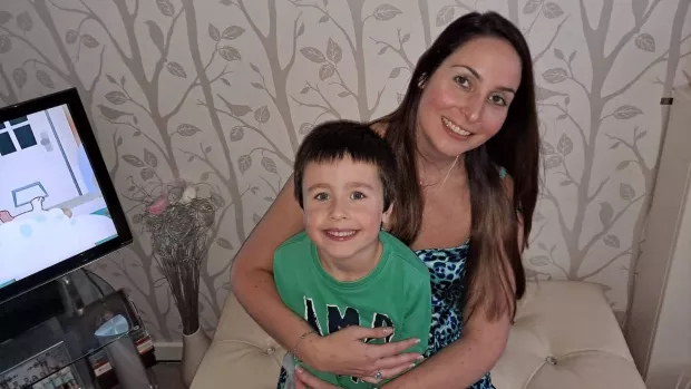 Michelle sits with her son on her lap, they are both smiling.