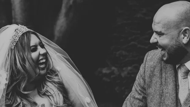 The photo is in black and white. It shows Hannah and her husband on their wedding day, smiling at each other.