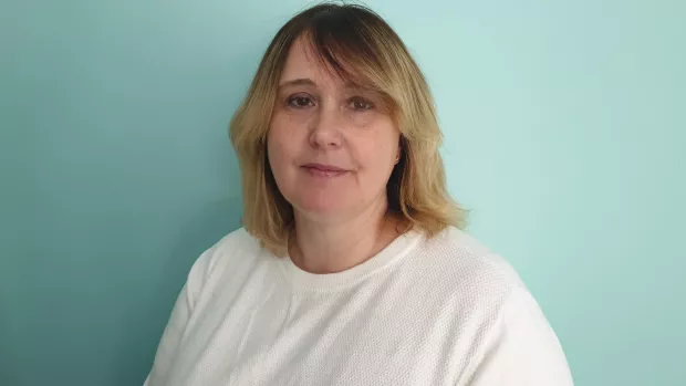 The photo shows Sam Walker smiling at the camera against a pale blue background.