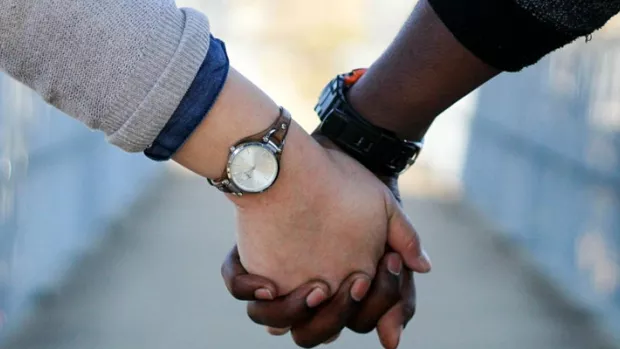 The photo shows two people holding hands