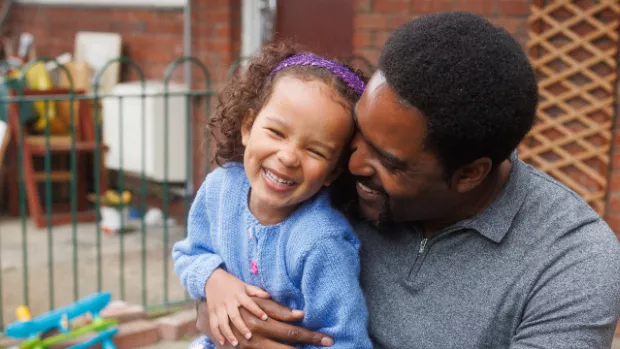 A man sitting outside, holding his daughter