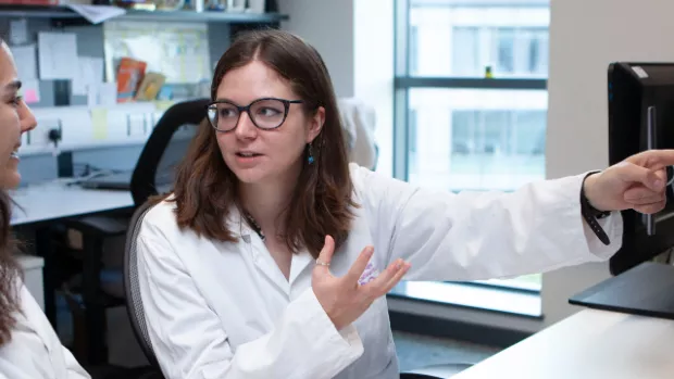 Two researchers having a discussion in front of a computer screen