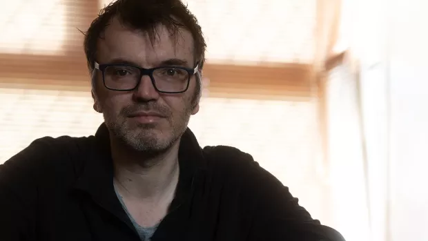 Close up of Martin, wearing glasses against a blurred background