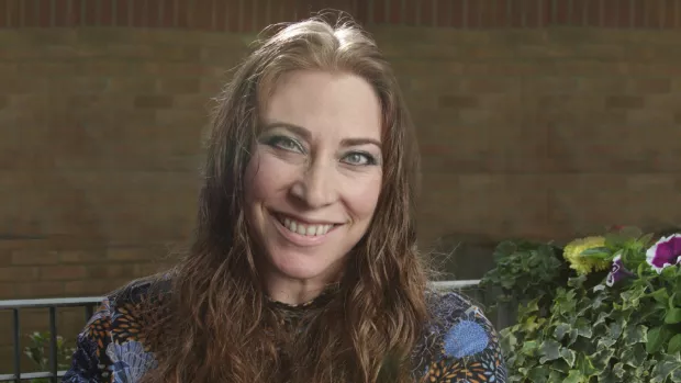 The photo shows Shana sitting on a bench outside, smiling at the camera.