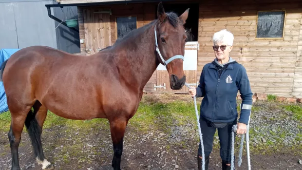 Anne Brown standing outside a stable with her bay mare, Tomboy.