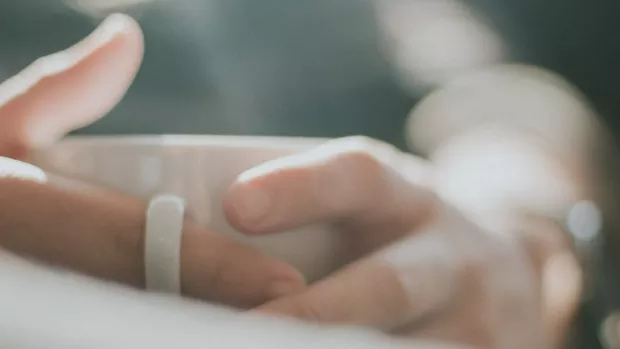 The photo shows a person's hands holding a white mug