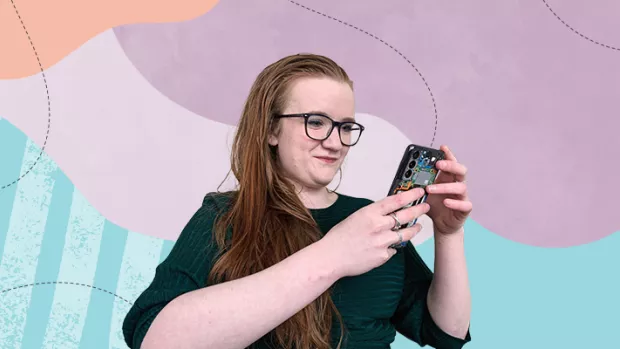 White woman with red hair and glasses looking at her smart phone