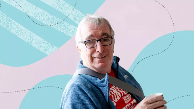 White man wearing glasses and a denim shirt looks to camera