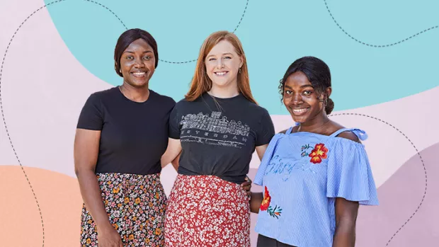 Group of three young women with arms around each other. Tallest girl on left is Black with her hair pulled back. Middle girl is White with red hair and shortest girl is Black with her hair pulled back