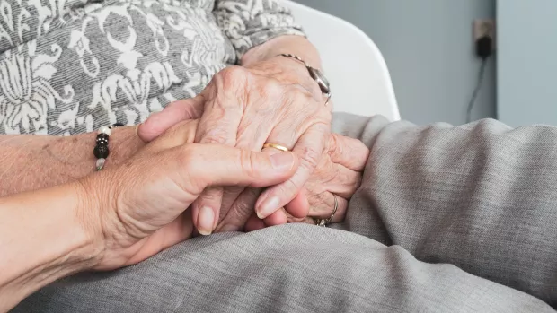 Close up of hands held in the lap of someone wearing grey trousers