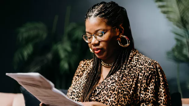 Cherelle wearing leopard print top looking down at a script. Photo by Ralu Chase.