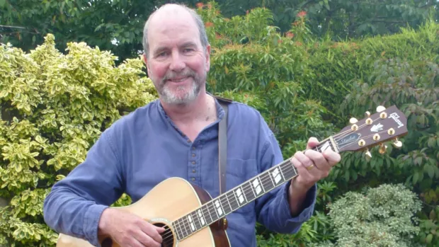 Dave outside holding an acoustic guitar