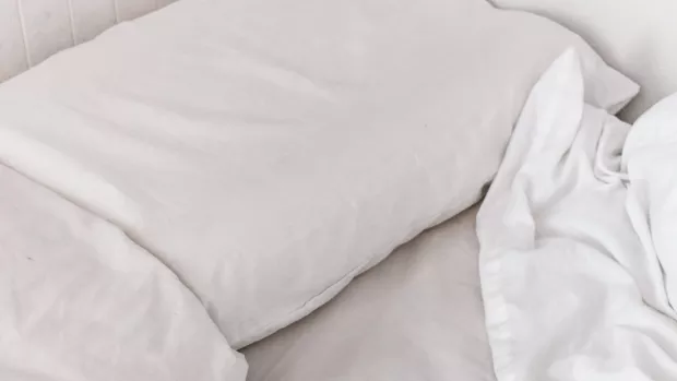 The photo shows white pillows and a duvet