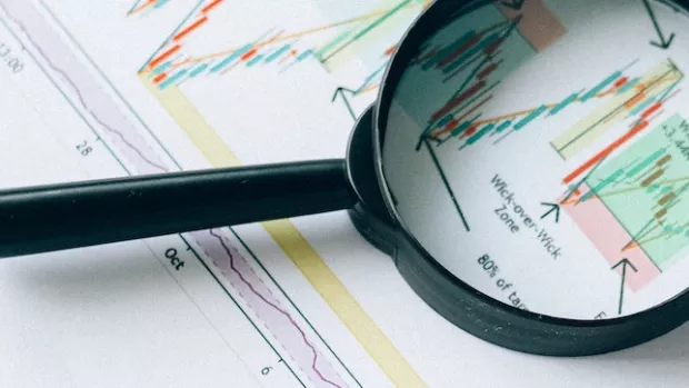 A magnifying glass on top of papers showing diagrams and charts
