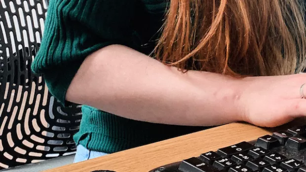 Close up of a woman's hands as she types at a keyboard