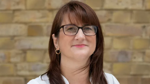 Image shows a woman with long brown hair smiling 