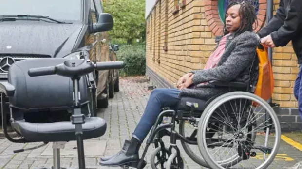 Woman with MS in wheelchair by a car